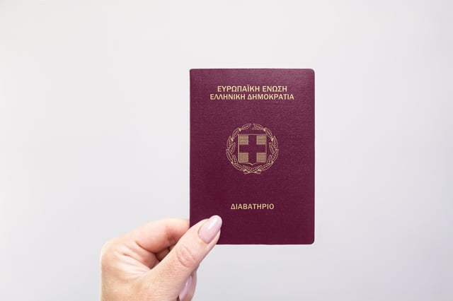 Greece Held Passport In Hand Against A Plain White Background