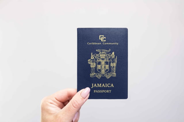 Jamaica Held Passport In Hand Against A Plain White Background