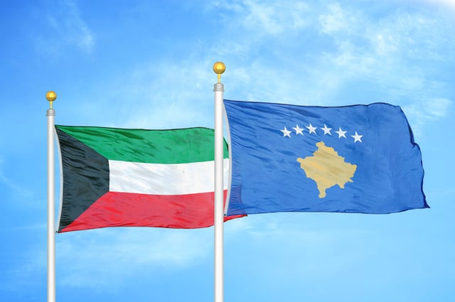 Kuwait And Kosovo Two Flags On Flagpoles And Blue Cloudy Sky Background