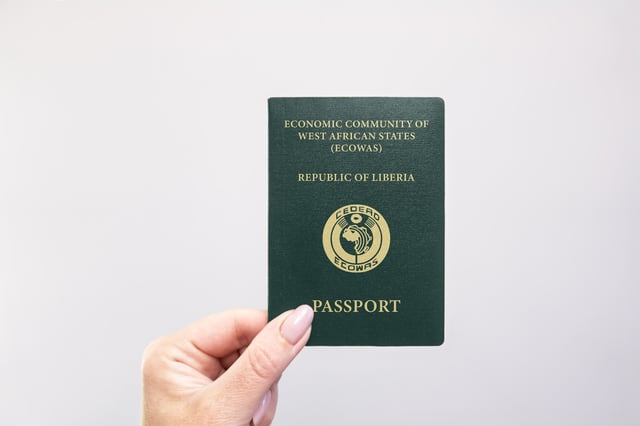 Liberia Passport Held In Hand Against A Plain White Background