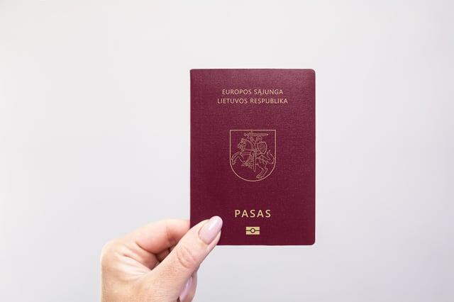 Lithuania Passport Held In Hand Against A Plain
