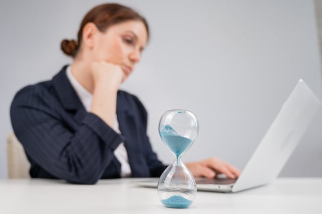 Businesswoman flipping hourglass at desk