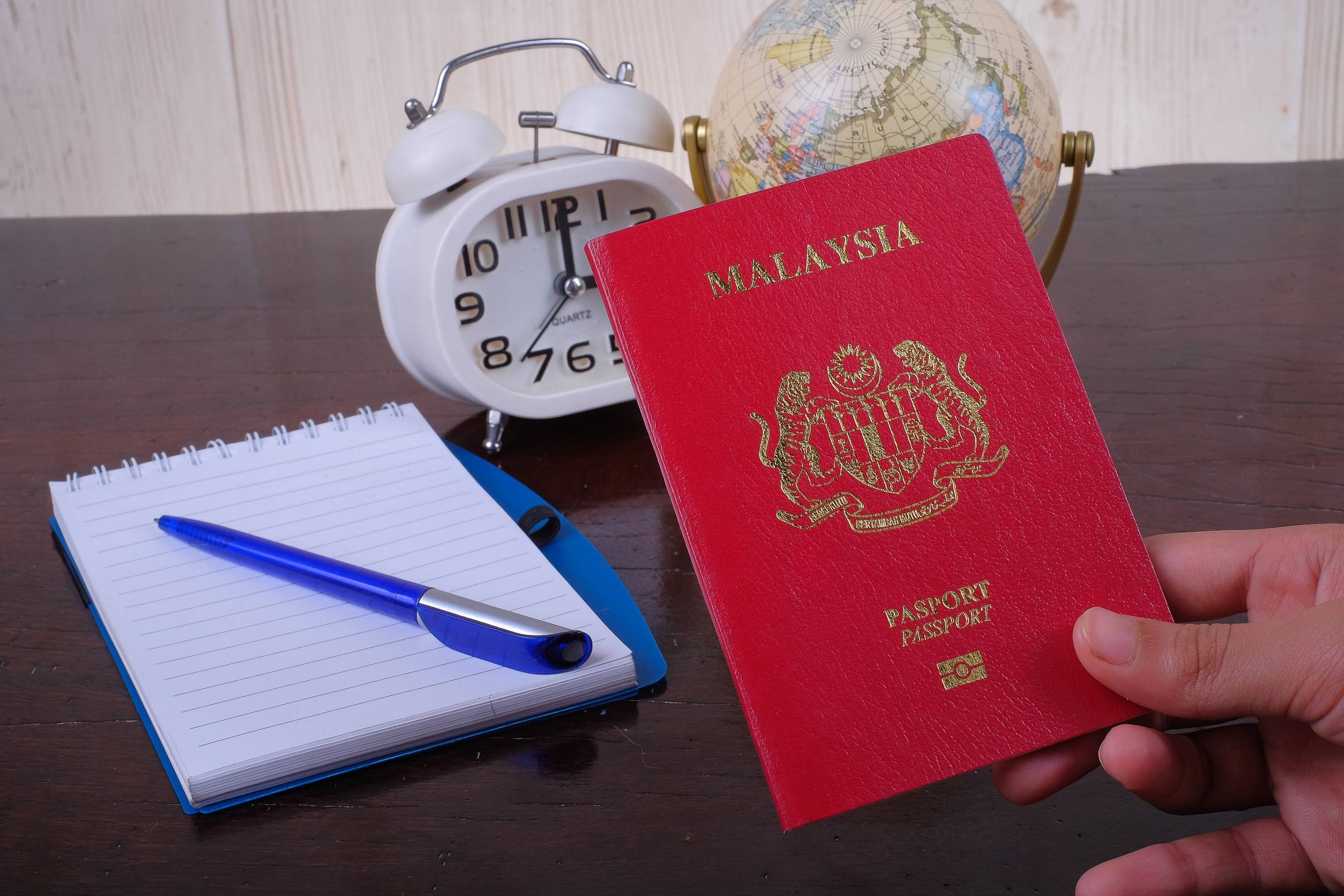 accessories-of-travel-concept-with-note-book-globe-clock-money-and-alarm-hand-holding