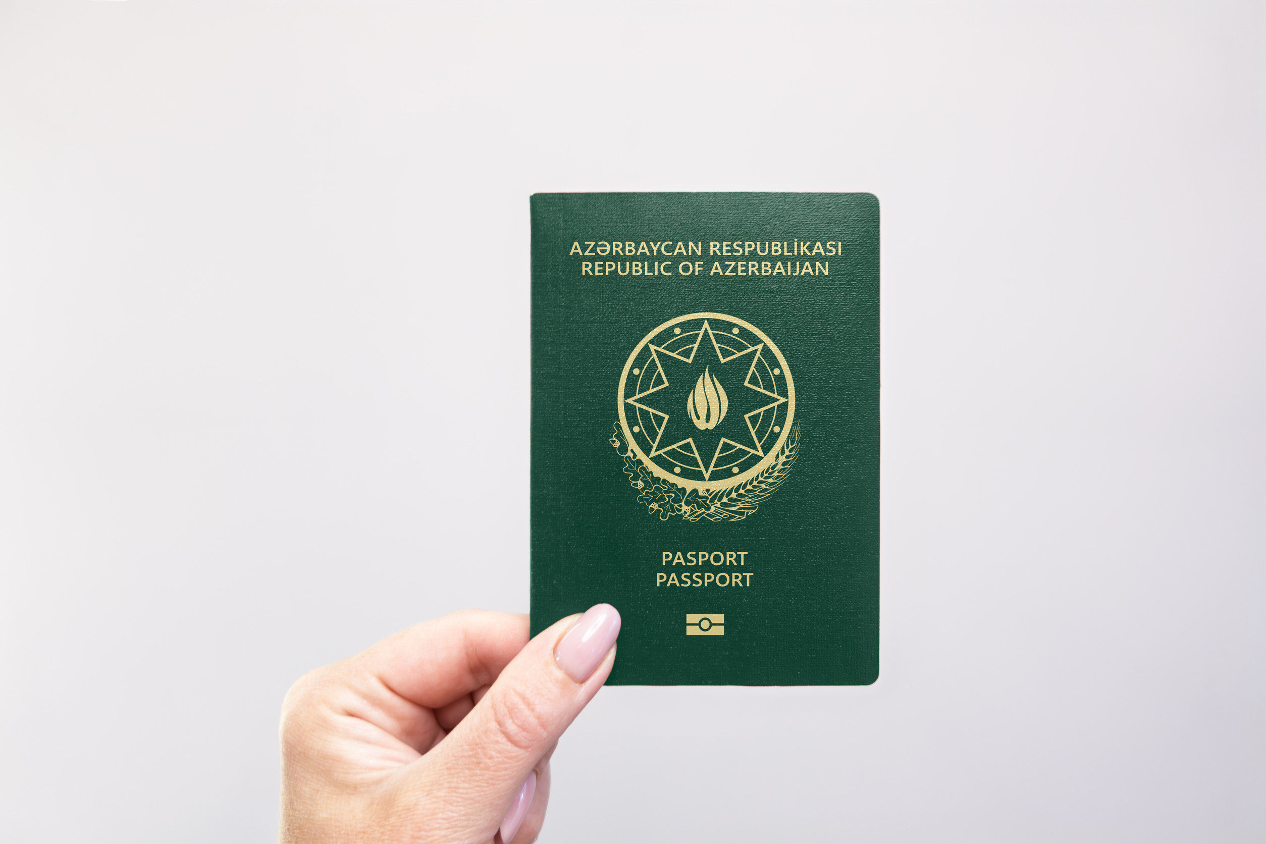 Azerbaijan Held Passport In Hand Against A Plain White Background