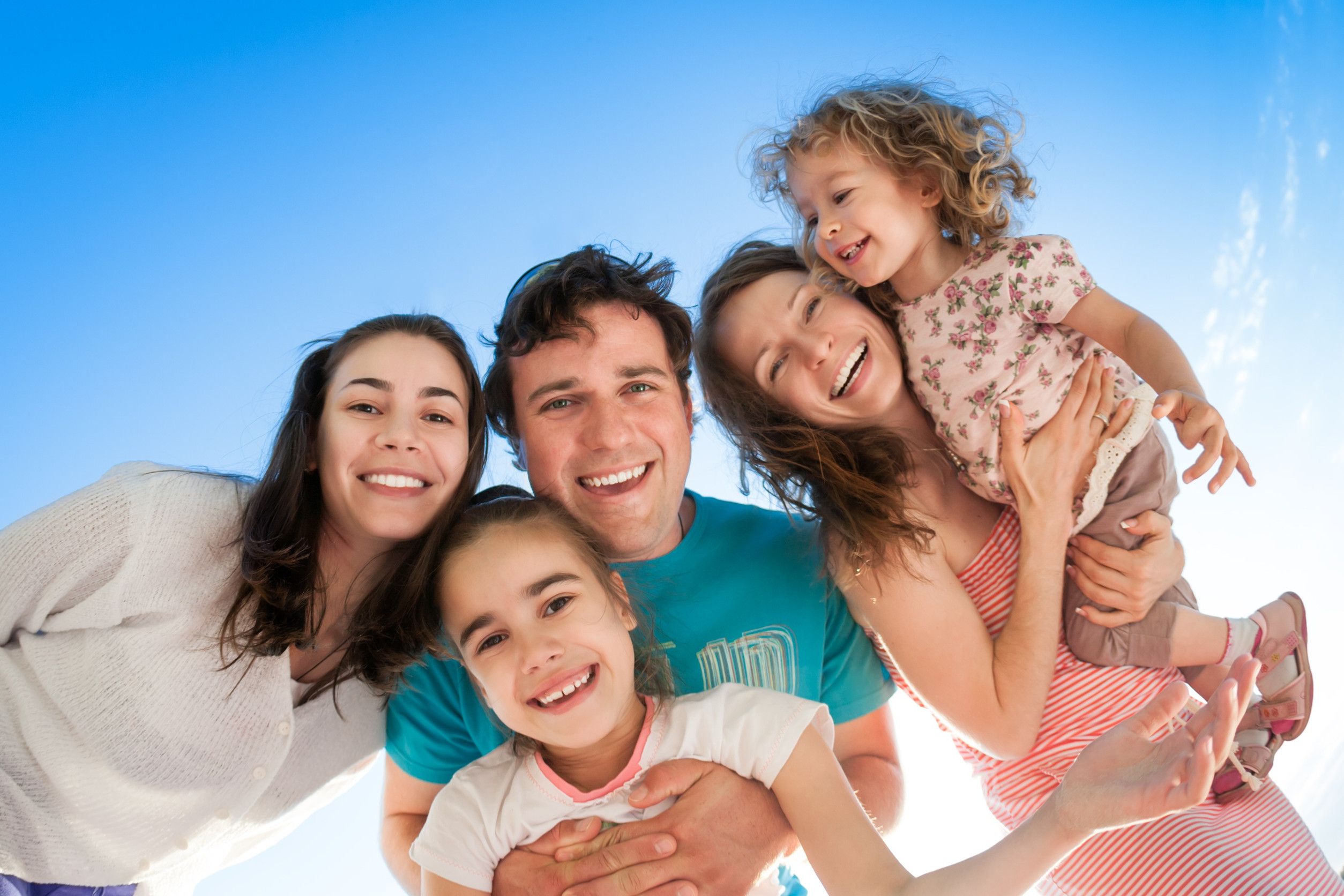 group-of-happy-smiling-people-against-blue-sky-low-angle-view-fisheye-shoot