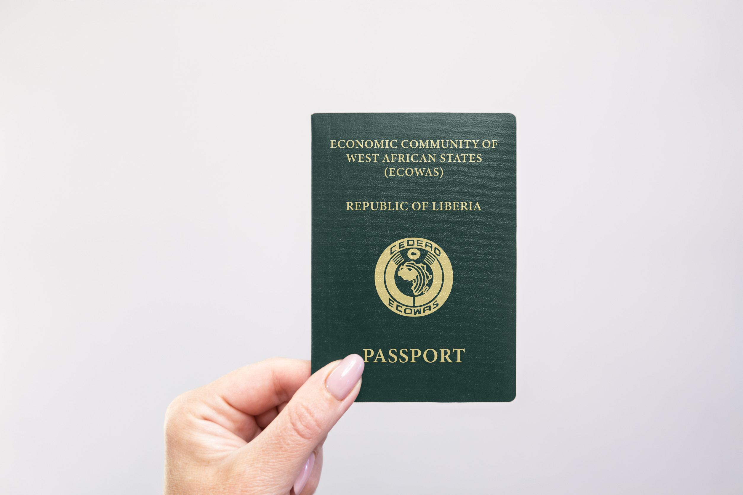 Liberia Passport Held In Hand Against A Plain White Background