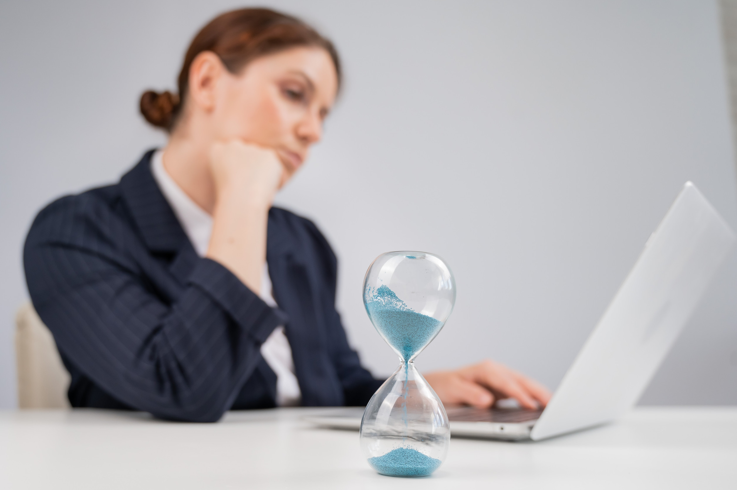 Business Woman Keeps Track Of Time On An Hourglass While Working